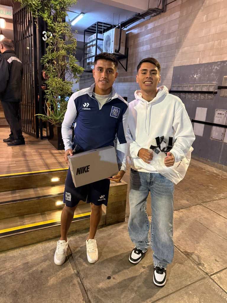Dos personas mostrando una caja de calzado y una bolsa.