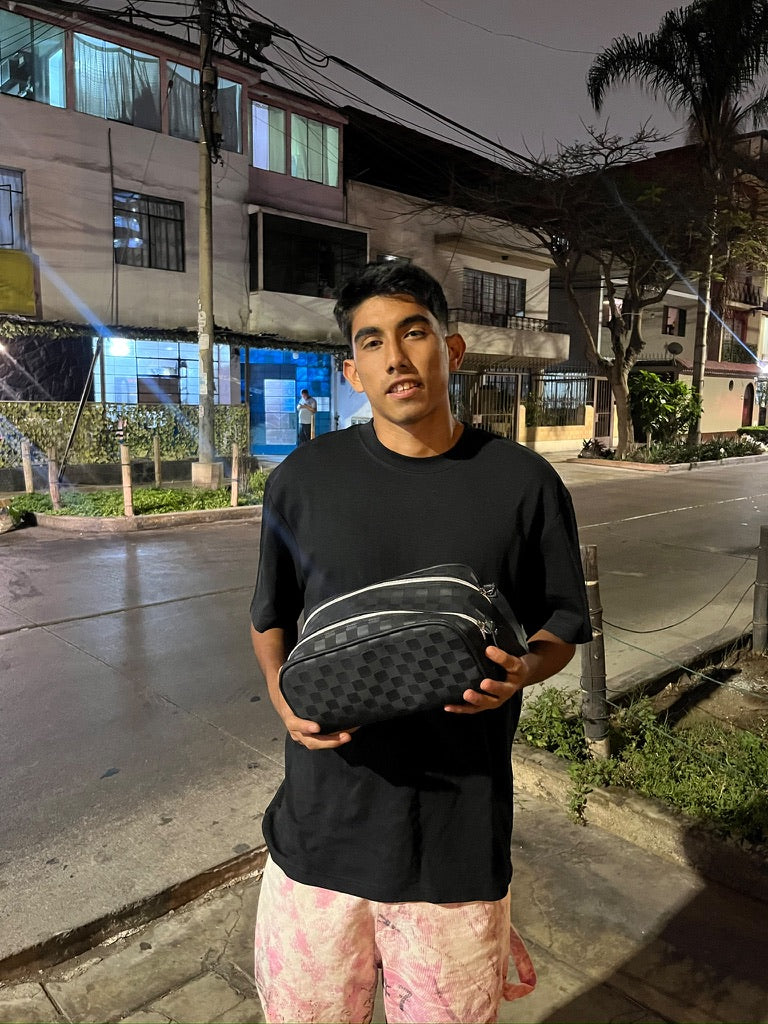 Una persona mostrando un neceser de patrón cuadriculado.