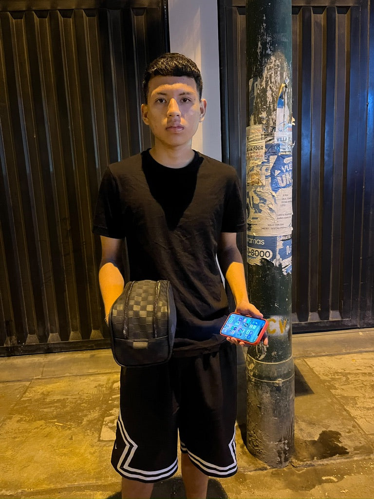 Una persona sosteniendo un neceser de patrón cuadriculado.